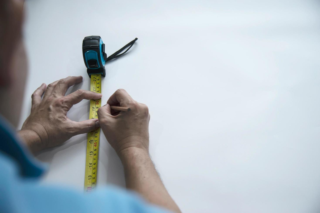 Man using measure hand tool doing wallpaper cutting work in home