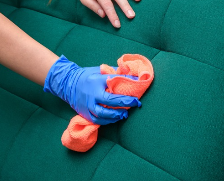 a hand applying soft dump cloth on a fabric sofa